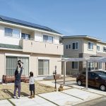 大きなカーポートとグリーンの屋根が特徴的な外観